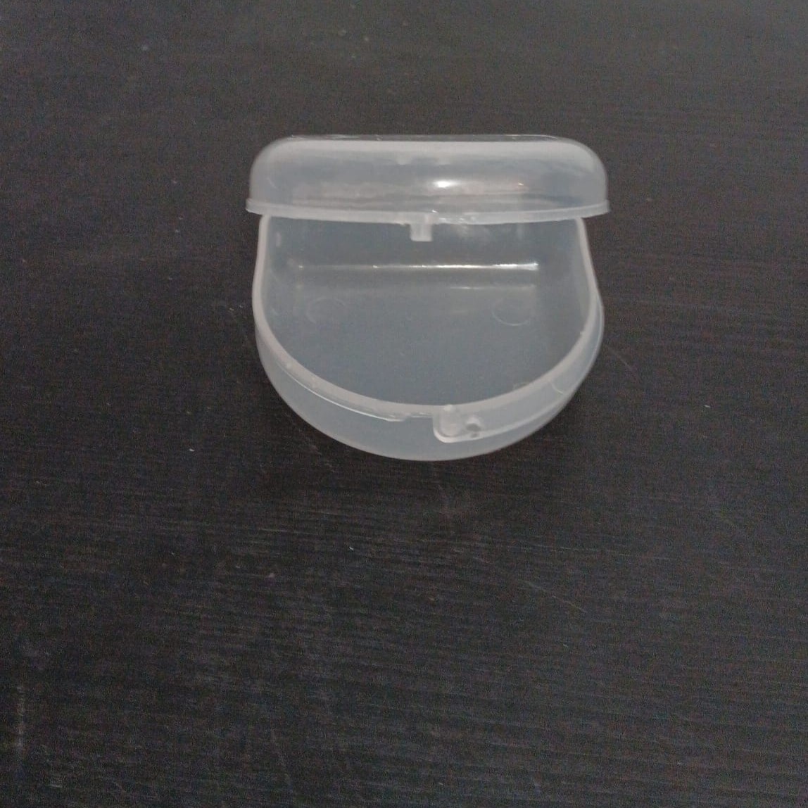 A plastic retainer case that opens and closes using a snap latch, suggesting a pressing interaction.