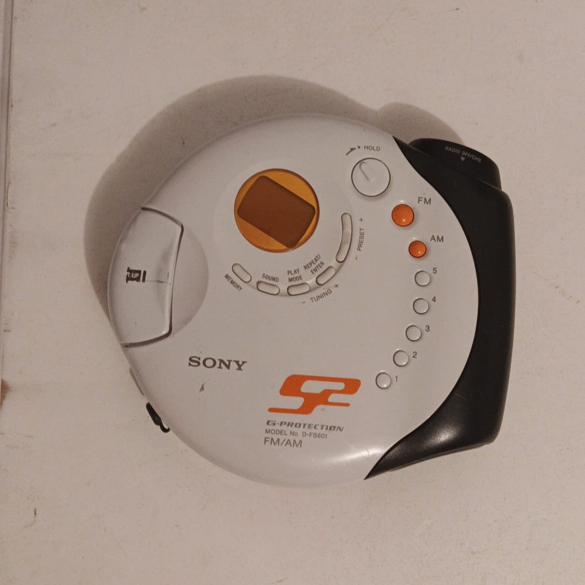 A portable CD player with buttons and a hinged lid that suggest pressing and opening.