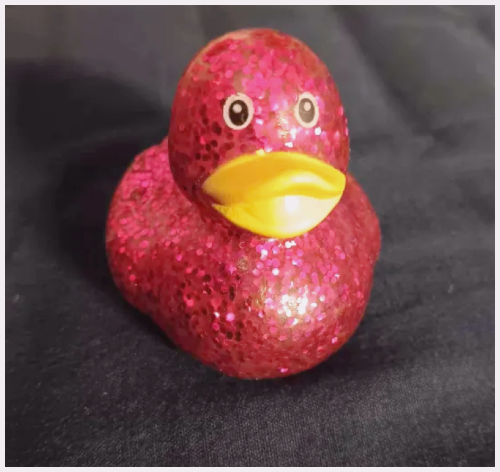 Front of a pink sparkly bathtub duck toy.